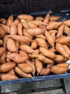 A field crate filled with small, pale-orange petite sweet potatoes